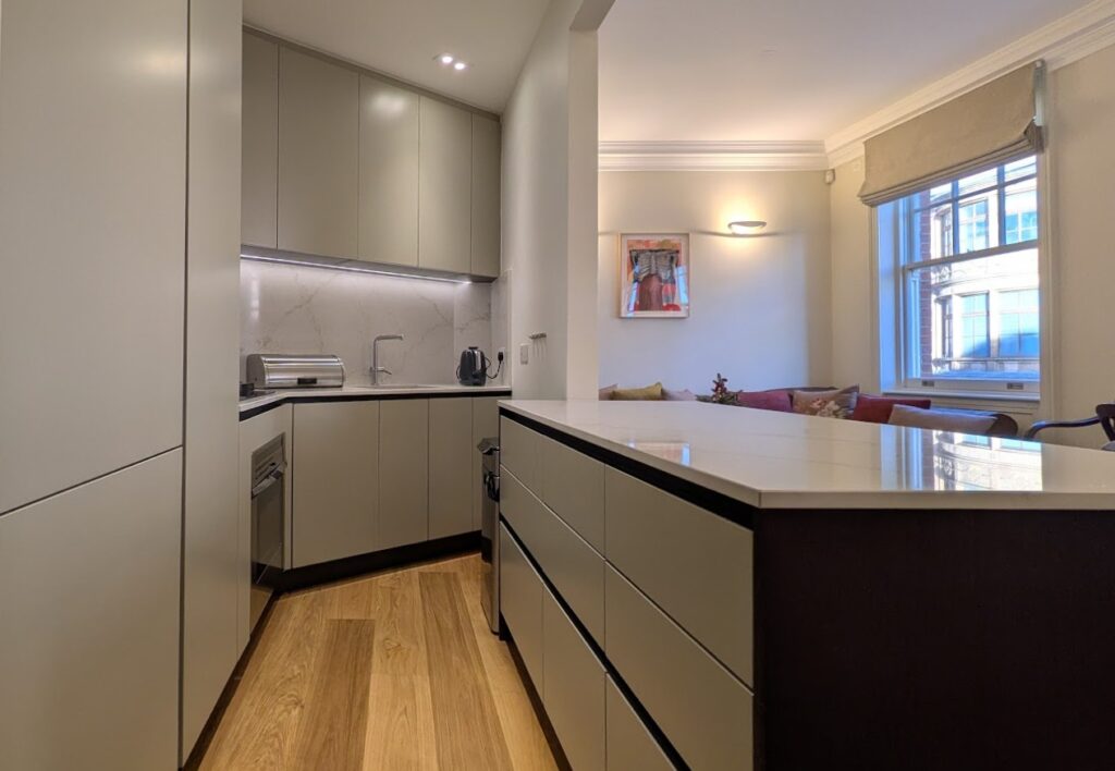 Modern Gentili kitchen with neutral cabinetry, marble-effect backsplash and large peninsula overlooking a bright living space.